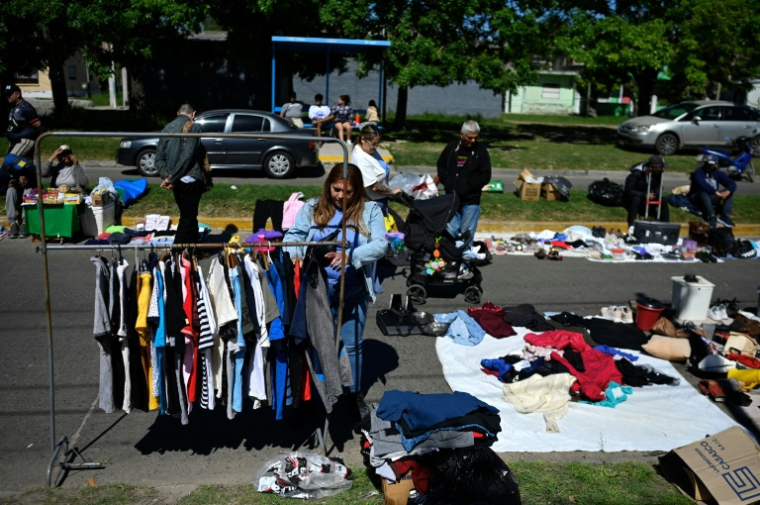 Une passante regarde des vêtements d'occasion sur un marché de rue à Villa Fiorito, dans la banlieue de Buenos Aires, le 19 octobre 2025 en Argentine ( AFP / Luis ROBAYO )