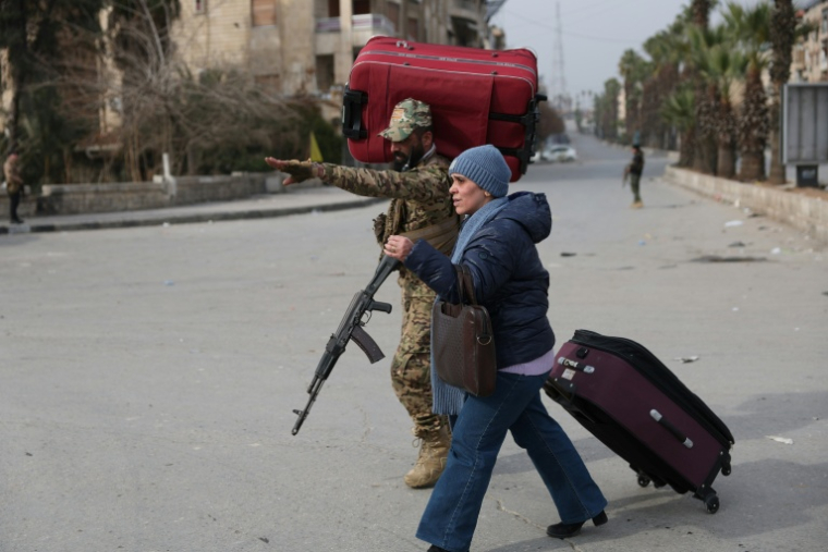 Un soldat syrien aide un habitant fuyant les quartiers majoritairement kurdes de Cheikh Maqsoud et Achrafieh  dans la ville d’Alep, au nord de la Syrie, le 8 janvier 2026 ( AFP / OMAR HAJ KADOUR )