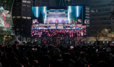 Des fans de BTS regardent le concert de retour du groupe de K-pop sur écran géant, le 21 mars 2026 à Séoul ( AFP / Roland DE COURSON )