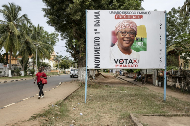 Un piéton passe devant une affiche de campagne pour le président sortant et candidat à la présidence Umaro Sissoco Embalo à Bissau, le 21 novembre 2025, à l'approche des élections générales en Guinée-Bissau prévues le 23 novembre 2025. ( AFP / PATRICK MEINHARDT )