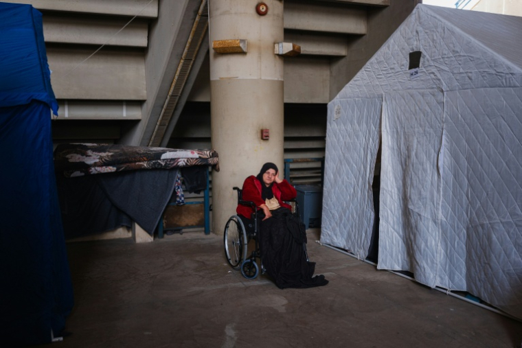Une femme en fauteuil roulant devant les tentes installées dans le stade Camille Chamoun, transformé en centre d'accueil et d'hébergement pour personnes déplacées, à Beyrouth, le 27 mars 2026 au Liban ( AFP / Dimitar DILKOFF )