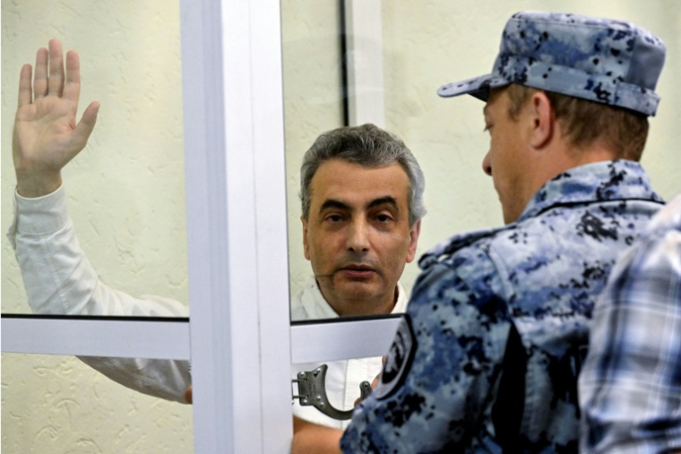 Un huissier passe les menottes à Lev Chlosberg, vice-président du parti antiguerre russe Iabloko, condamné à 11 ans de prison pour avoir critiqué l'offensive de Moscou en Ukraine, au tribunal de Pskov, dans le nord-ouest de la Russie, le 17 août 2026 ( AFP / Olga MALTSEVA )