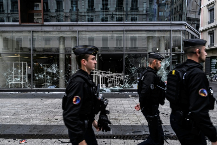 Des gendarmes en patrouille passent devant des boutiques endommagées à Lyon, au lendemain d'une manifestation contre la vie chère, le 18 octobre 2026 ( AFP / JEFF PACHOUD )