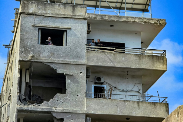 Des habitants dans un immeuble endommagé par une frappe israélienne octurne à Tyr, dans le sud du Liban, le 16 mai 2026 ( AFP / Kawnat HAJU )