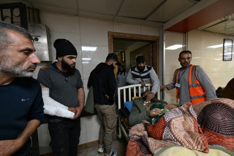 Des personnes autour d'un homme blessé allongé sur un lit d'hôpital à l'hôpital al-Mouwassat de Damas, à la suite d'une opération menée par les forces israéliennes dans le village de Beit Jinn dans le sud de la Syrie, le 28 novembre 2025 ( AFP / LOUAI BESHARA  )