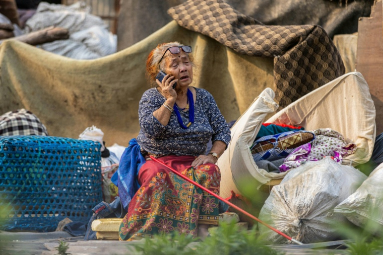 Une femme au téléphone lors de la démolition ordonnée par les autorités des bidonvilles abritant des milliers de personnes le long des berges de la capitale népalaise Katmandou, le 25 avril 2026 ( AFP / PRABIN RANABHAT )