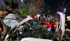 Des passants et des secouristes inspectent la carcasse du minibus dans lequel une bombe a explosé, à Jaramana, près de la capitale syrienne, Damas, le 6 août 2026 ( AFP / LOUAI BESHARA )