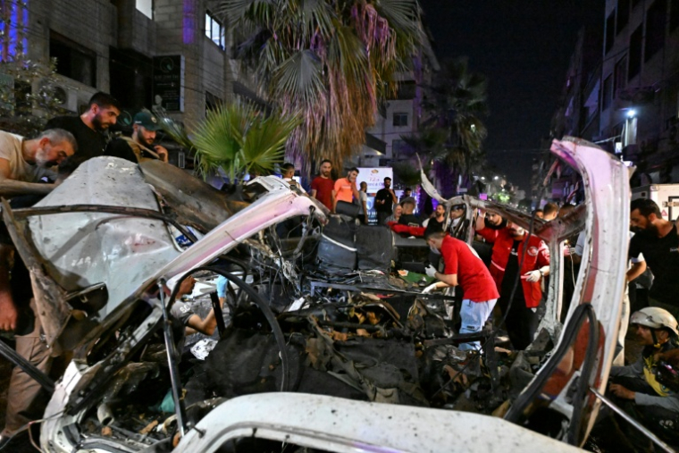 Des passants et des secouristes inspectent la carcasse du minibus dans lequel une bombe a explosé, à Jaramana, près de la capitale syrienne, Damas, le 6 août 2026 ( AFP / LOUAI BESHARA )