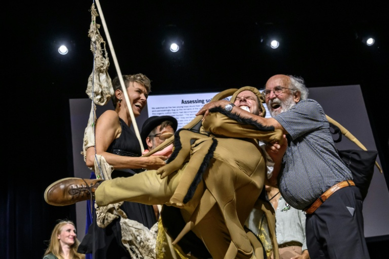 Le journaliste scientifique suisse Atlant Bieri (centre) échange avec Michel Mayor (droite), lauréat du prix Nobel de physique 2019, aux côtés de la biotechnologiste suisse Pia Viviani (gauche), lors de la cérémonie des prix Ig Nobel 2026 à Zurich, le 3 septembre 2026 ( AFP / Fabrice COFFRINI )