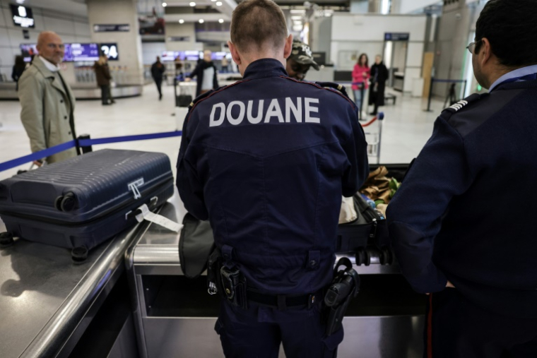 Des douaniers inspectent les bagages de passagers à l'aéroport de Roissy-Charles-de-Gaulle, au nord de Paris, le 21 mars 2025 ( AFP / Thibaud MORITZ )
