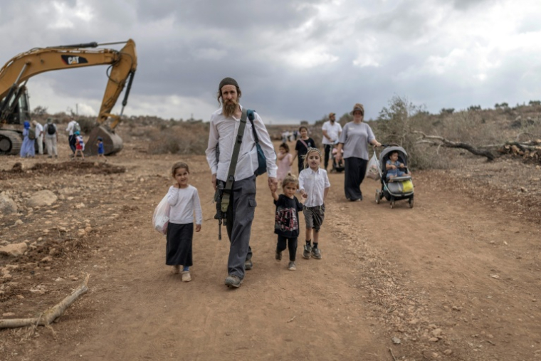 Des familles israéliennes marchent sur la route reliant les colonies de Ganim et de Kadim, à la périphérie de la ville palestinienne de Jénine, en Cisjordanie occupée, le 30 septembre 2026 ( AFP / Ilia YEFIMOVICH )