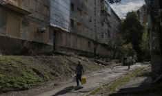 Une femme passe devant un immeuble résidentiel endommagé lors d'une frappe aérienne russe dans la ville d'Izioum, dans la région de Kharkiv, à l'est de l'Ukraine, le 29 juillet 2026 ( AFP / Roman PILIPEY )