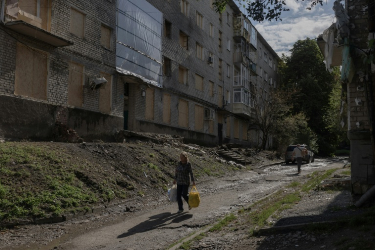 Une femme passe devant un immeuble résidentiel endommagé lors d'une frappe aérienne russe dans la ville d'Izioum, dans la région de Kharkiv, à l'est de l'Ukraine, le 29 juillet 2026 ( AFP / Roman PILIPEY )