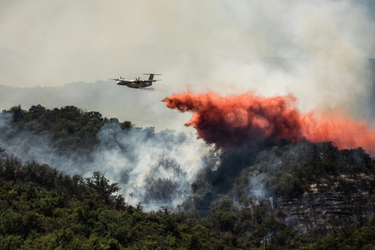 Un avion Dash Q400-MRE de la Sécurité civile largue du produit retardant sur un incendie de forêt qui fait rage près de la commune de Bouleternère, dans les Pyrénées-Orientales, le 6 juillet 2026 ( AFP / Jean-Christophe MILHET )