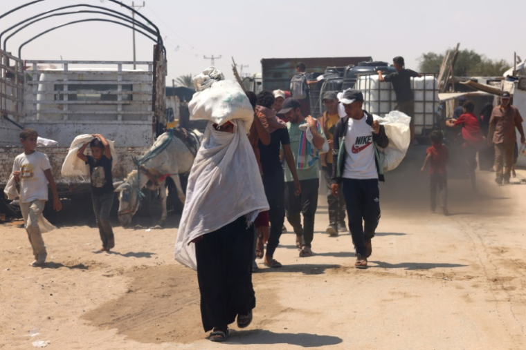 Des Palestiniens transportent de l'aide humanitaire dans le quartier de Mawasi à Rafah, dans le sud de la bande de Gaza, le 18 août 2025 ( AFP / - )
