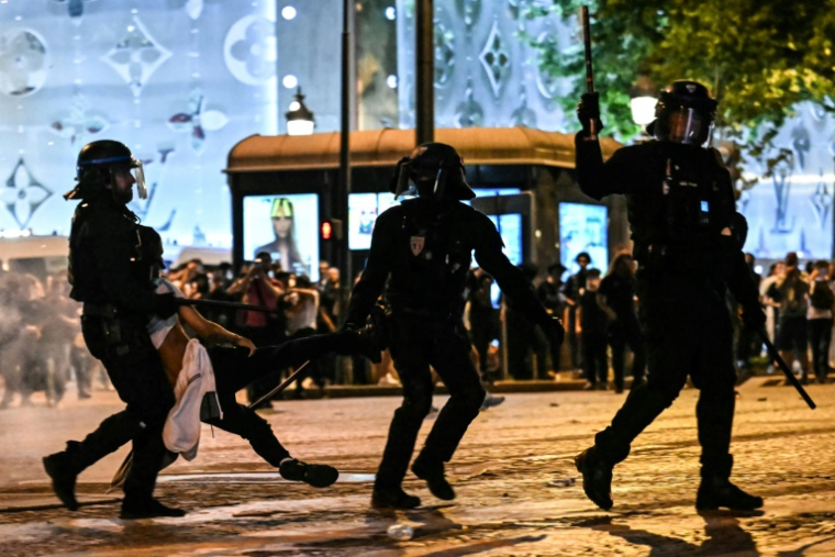Des policiers anti-émeute interpellent une personne alors que des supporters du Paris Saint-Germain célèbrent la victoire de leur club sur l'avenue des Champs-Élysées, le 31 mai 2025  ( AFP / LOU BENOIST )