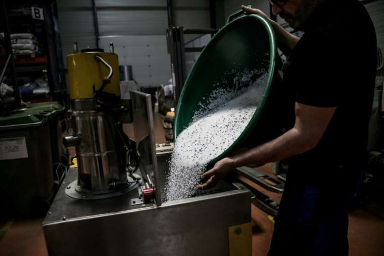 Un employé de l'usine Francia, spécialisée dans l'injection de plastique, déverse des granulés de plastique dans une machine, le 16 avril 2026 à Bellignat, dans l'Ain  ( AFP / JEFF PACHOUD )