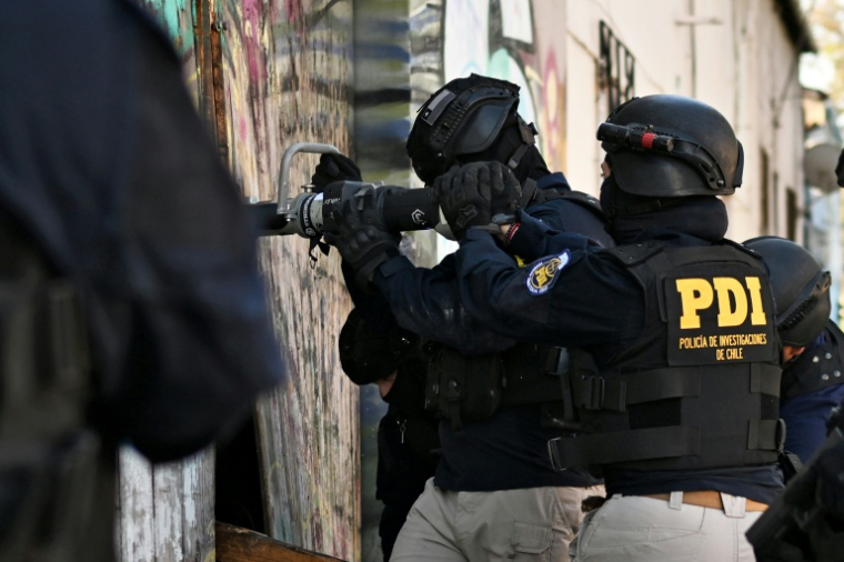 Des policiers pénètrent dans une habitation lors d'une opération antidrogue   à Santiago, le 11 décembre 2025  ( AFP / Rodrigo ARANGUA )