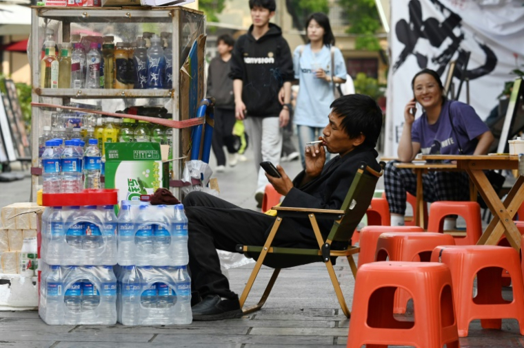 Un vendeur fume sur un marché à Yuxi, dans la province du Yunnan, le 31 mars 2025 dans le sud-ouest de la Chine ( AFP / GREG BAKER )