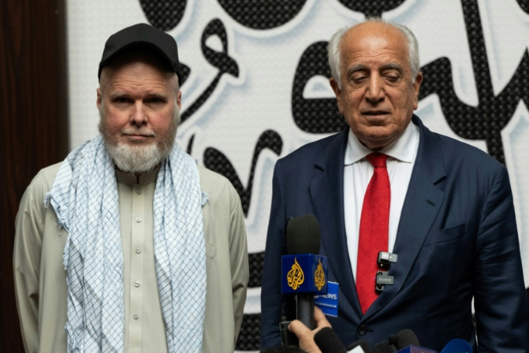 L'Américain Dennis Coyle (g) et l'ancien représentant spécial américain pour l'Afghanistan Zalmay Khalilzad, après sa libération par les talibans, le 24 mars 2026 à l'aéroport de Kaboul, en Afghanistan ( AFP / Wakil KOHSAR )
