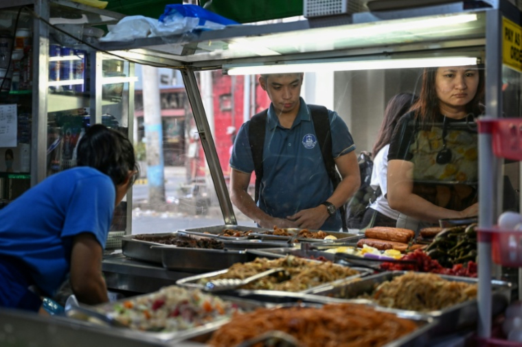 Des gens achetant de quoi manger dans une cantine de rue à Manille, le 7 avril 2026 ( AFP / Jam STA ROSA )