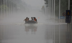 Des gens traversent en bateau une route inondée après les pluies du typhon Doksuri, à Zhuozhou en Chine