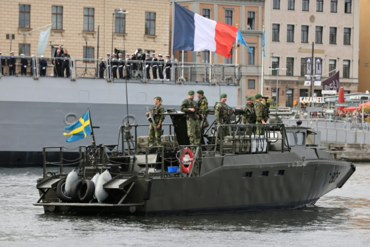 Des soldats suédois à bord d'une embarcation d'assaut rapide CB90 de la marine suédoise, devant la frégate française *Amiral Ronarc’h*, à Stockholm, le 31 août 2026 en Suède, avant la signature d'un contrat portant sur l'acquisition par la Suède de quatre frégates française de défense et d'intervention (FDI) ( AFP / Ludovic MARIN )