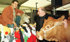 Philippe Soulas (D) tient la vache qu'il s'est vu offrir par le cou, le 09 octobre 1999, après avoir remporté le prix de l'humour vache au 18e Salon International de dessin de presse et d'humour de Saint-Just-Le-Martel (Haute-Vienne). Ivan Sigg, proclamé vainqueur du prix de l'humour tendre a reçu un agneau du Limousin.      ( AFP / MICHEL HERMANS )