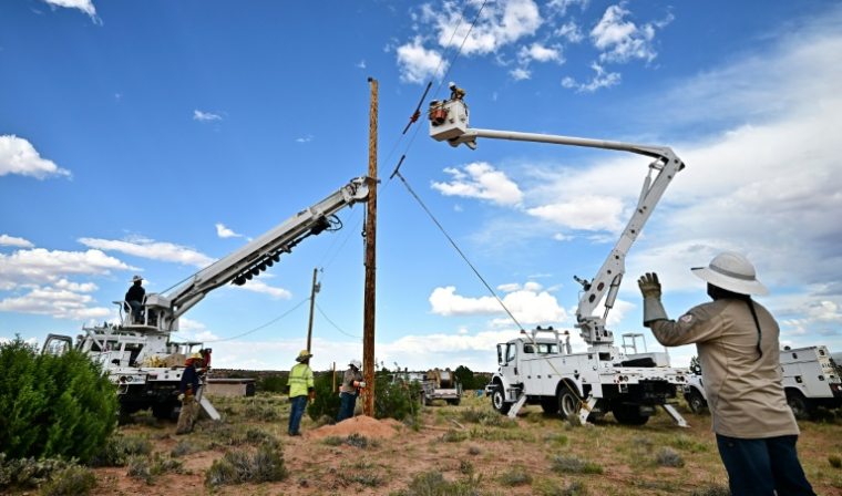 Des ouvriers plantent un poteau électrique à Tonalea, en Arizona, le 8 juillet 2025, dans le cadre d'un projet pour électrifier la réserve amérindienne Navajo ( AFP / Frederic J. BROWN )