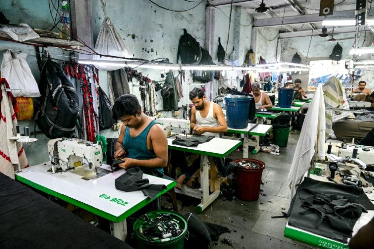 Des ouvriers dans une atelier de fabrication de vêtements dans le bidonville de Dharavi, le 12 juillet 2025 à Bombay, en Inde ( AFP / Indranil MUKHERJEE )