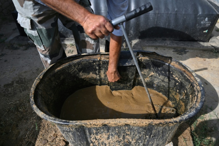 Un habitant déverse de la bouse de vache pour faire du biogaz dans un village du district de Bulandshahr, dans l'Uttar Pradesh, le 24 avril 2026 en Inde ( AFP / Arun SANKAR )