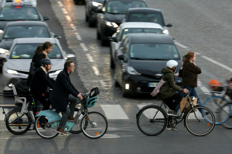 Des cyclistes traversent une rue de Paris à l'heure de pointe, le 8 octobre 2024 ( AFP / Thomas SAMSON )