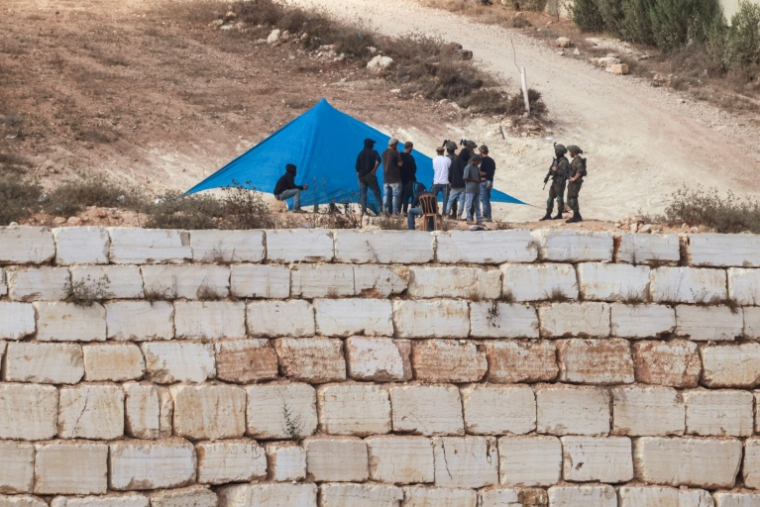 Des soldats israéliens près d'une tente installée par des colons israéliens devant l'entrée de la maison d'une famille palestinienne assiégée, dans le village de Qusra, au sud de la ville de Naplouse, en Cisjordanie occupée, le 14 août 2026 ( AFP / Jaafar ASHTIYEH )