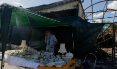Vadym vend des objets sur son étal du marché aux puces de Potchaïna endommagé par une frappe russe, le 9 août 2026 à Kiev, en Ukraine ( AFP / Tetiana DZHAFAROVA )