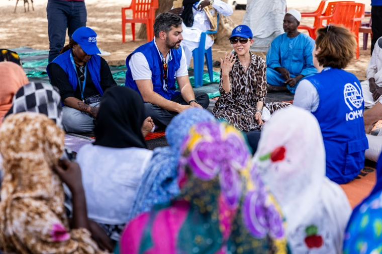 La directrice générale adjointe de l'Organisation internationale pour les migrations (OIM), SungAh Lee (d), s'entretient avec des Tchadiens de retour au pays à Adré, le 8 juin 2026 au Tchad ( AFP / Joris Bolomey )