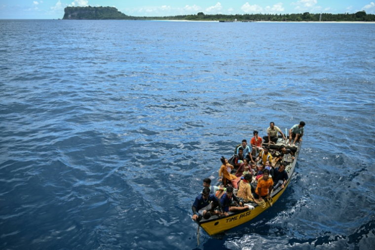 Des passagers sur un canot s'apprêtent à monter à bord  du ferry Kalighat, l'unique lien entre Chowra et Car Nicobar, deux minuscules morceaux de l'archipel indien des Andaman-et-Nicobar, en plein cœur de l'océan Indien, le 30 mars 2026 ( AFP / R. Satish BABU )