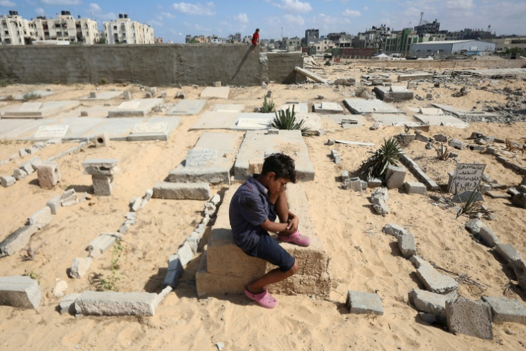 Un enfant assis sur une tombe d'un cimetière de Khan Younès le 25 septembre 2025 ( AFP / Omar AL-QATTAA )
