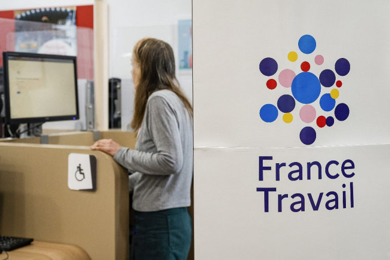 (FILES) A woman uses a computer next to a sign which reads as "France Travail" and displaying its logo at one of France's public employment agencies France Travail in Dammarie les Lys, northern France, on April 23, 2024. The number of jobseekers registered with France Travail rose by 3.9% in the fourth quarter of 2024 compared with the third quarter, the sharpest rise in unemployment in France (excluding Mayotte) in a decade outside the Covid crisis, according to figures published on January 27, 2025 by the Ministry of Labor. (Photo by Geoffroy VAN DER HASSELT / AFP) ( AFP / GEOFFROY VAN DER HASSELT )
