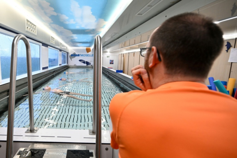 L'enseignant Thomas Rochet apprend à nager à des écoliers dans le camion-piscine du département de Moselle, stationné à Verny, le 30 janvier 2026 ( AFP / Jean-Christophe VERHAEGEN )