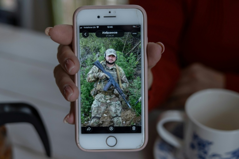 Nina, la mère du soldat ukrainien Iouriï Glodan tué au combat en septembre 2023 près de Bakhmout, montre une photo de son fils défunt, le 20 février 2026 à Odessa ( AFP / Oleksandr GIMANOV )
