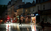 Des personnes courent se mettre à l'abri lors d'un violent orage dans le 20e arrondissement à Paris, le 25 juin 2025 ( AFP / Christophe DELATTRE )