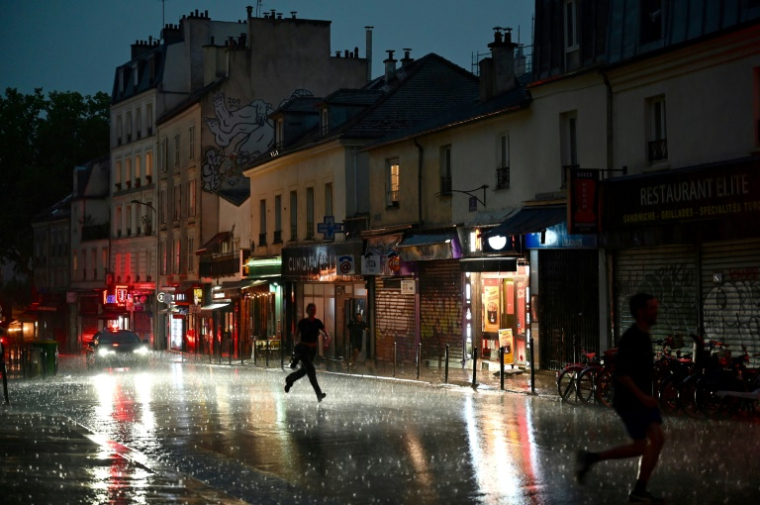 Des personnes courent se mettre à l'abri lors d'un violent orage dans le 20e arrondissement à Paris, le 25 juin 2025 ( AFP / Christophe DELATTRE )