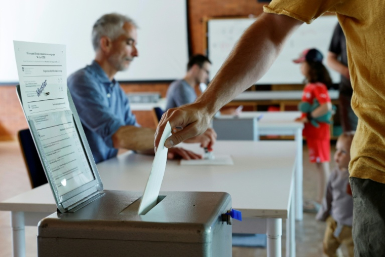 Un électeur vote sur une proposition de loi anti-immigration visant à plafonner la population du pays et sur un projet gouvernemental pour resserrer les critères d'accès au service civil, le 14 juin 2026 à Berne, en Suisse ( AFP / STEFAN WERMUTH )