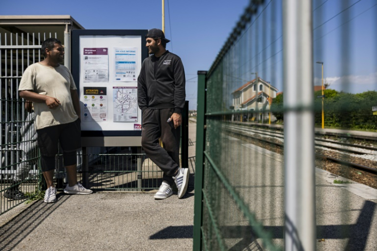Des Afghans en quête d'ombre à la gare de Wimille-Wimereux le 18 juin 2025, non loin des baigneurs venus nager et bronzer sur la côte d'Opale ( AFP / Sameer Al-DOUMY )