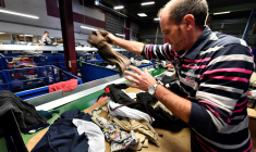 Un homme trie des vêtements dans un centre de recyclage Le Relais à Bordeaux, le 23 janvier 2019. ( AFP / GEORGES GOBET )