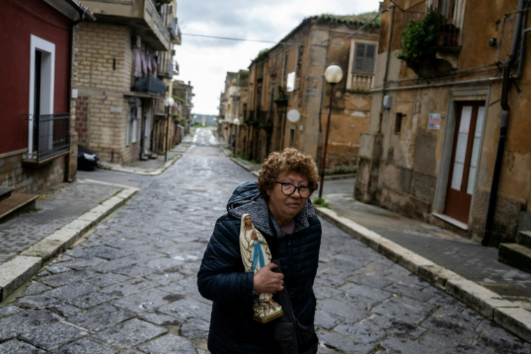 Une femme emporte une statue de la Vierge Marie en évacuant le 29 janvier 2026 son domicile situé dans la "zone rouge" de la ville de Niscemi, en Sicile, au bord d'une falaise qui s'est effondrée quelques jours plus tôt  ( AFP / MARCO BERTORELLO )