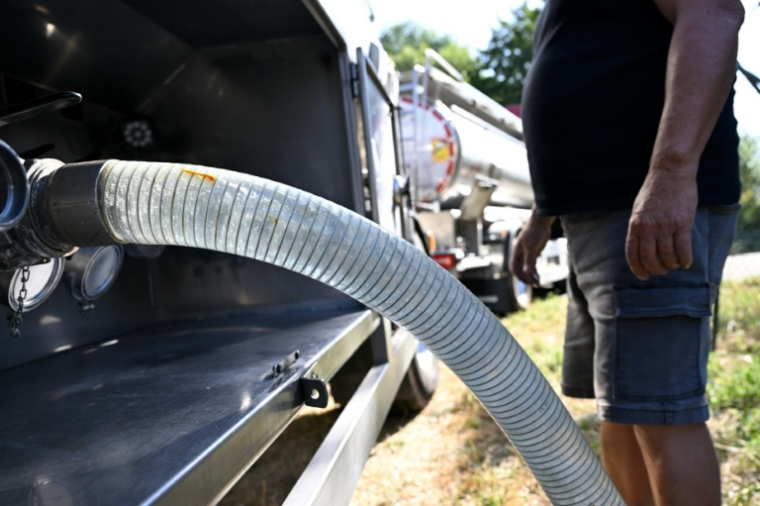 Un employé raccorde un tuyau à un camion-citerne transportant de l'eau potable pour approvisionner la commune de Sainte-Marie-aux-Mines, le 11 août 2026 dans le Haut-Rhin ( AFP / Jean-Christophe VERHAEGEN )