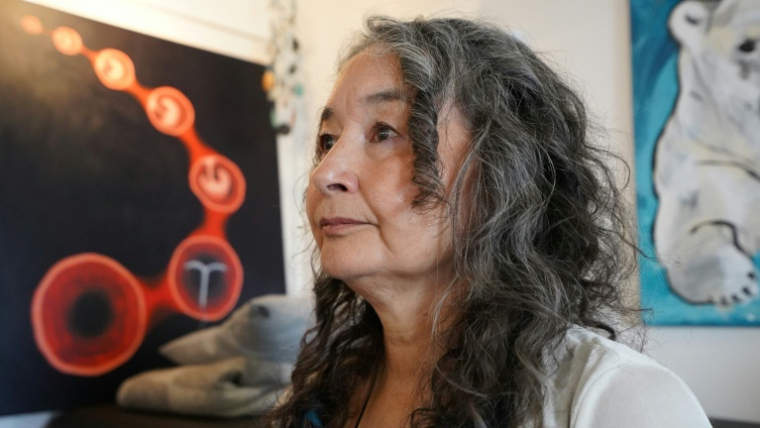 Naja Lyberth, psychologue et survivante de la campagne de stérilets imposés, pose devant un tableau représentant un utérus et un dispositif intra-utérin (DIU), à Nuuk, au Groenland, le 30 août 2024. ( AFP / James BROOKS )
