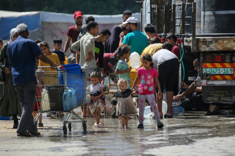 Des Palestiniens se rassemblent pour remplir leurs conteneurs d'eau à Nousseirat, dans le centre de la bande de Gaza, le 24 mai 2025 ( AFP / Eyad BABA )