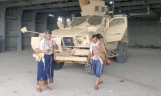 Un homme armé marche à côté d'un véhicule blindé, à Mocha